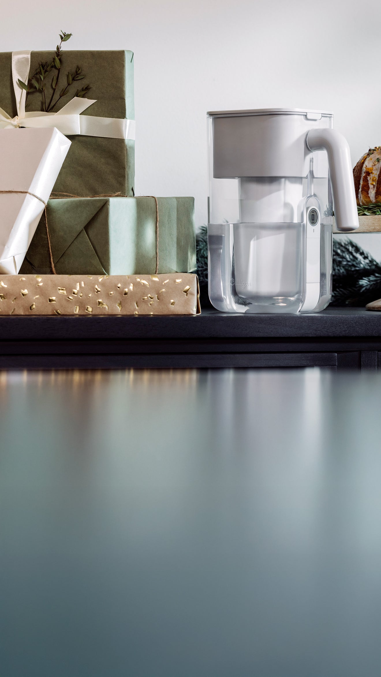 Clear glass carafe on a kitchen counter with decorative items in the background